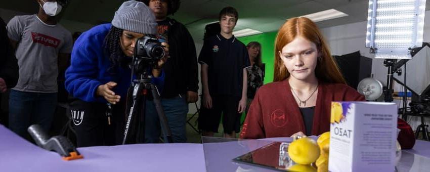 Students in a photography studio work on creating a product shot.